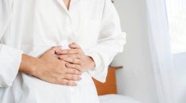 closeup woman having digestive system hand holding stomach pain