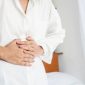 closeup woman having digestive system hand holding stomach pain